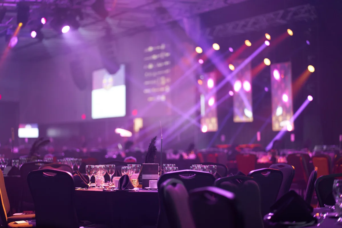 Salle de gala d'entreprise avec tables rondes dressées et scène éclairée