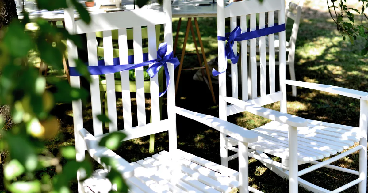 Deux chaises blanches décorées de rubans bleus, installées pour les mariés