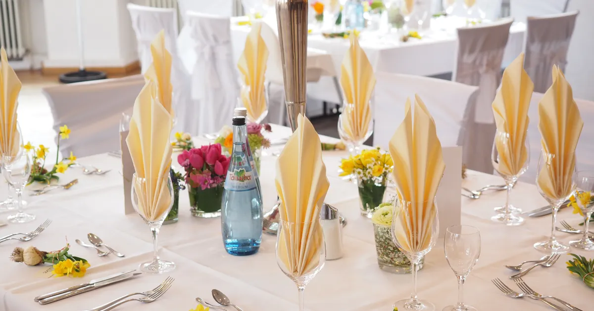 Wedding reception table set with folded napkins, glassware and fresh flowers