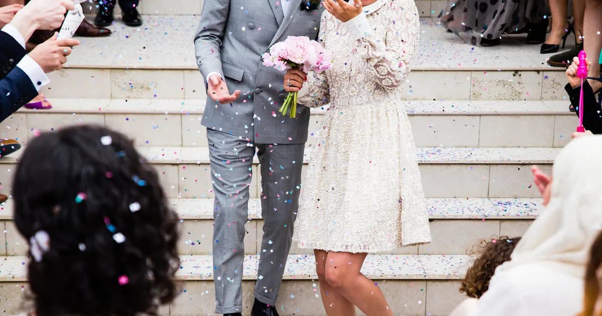Newlyweds walking down the steps as guests throw confetti